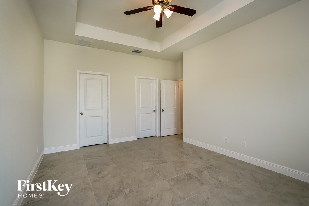 a empty living room with two doors and a ceiling fan