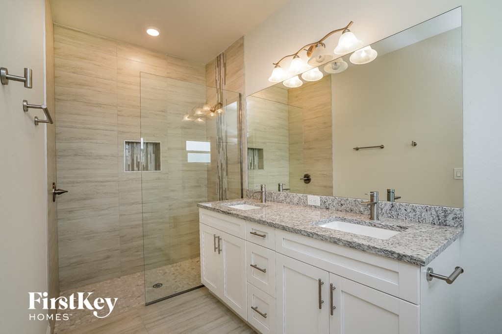 a bathroom with white cabinets and a shower and a sink