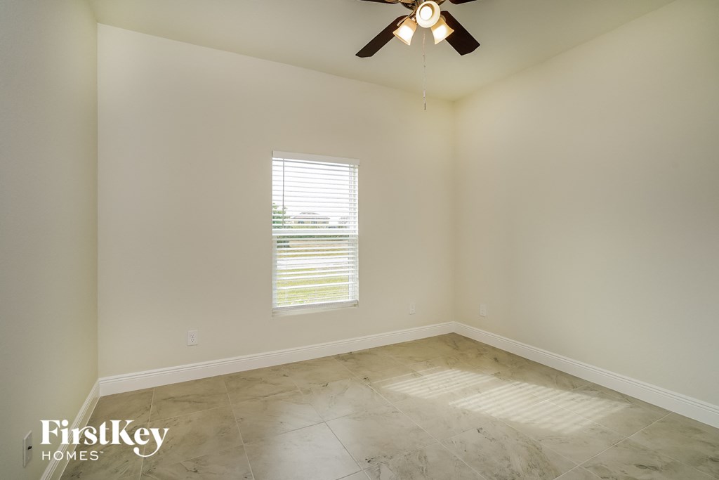 an empty room with a ceiling fan and a window