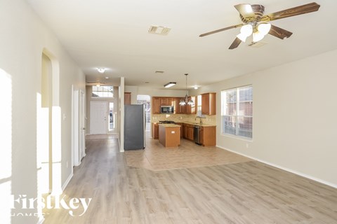 A spacious living room with a ceiling fan and lighting fixtures.