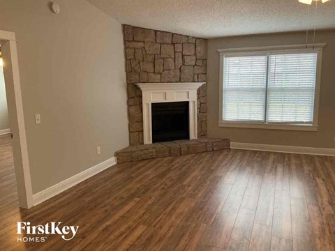 a living room with a stone fireplace and wooden floors