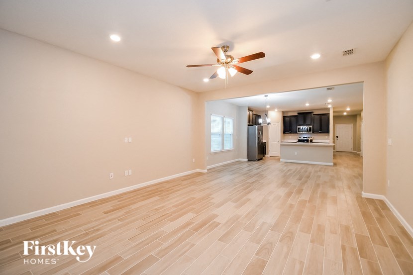 A spacious living room with a wood floor and a ceiling fan.