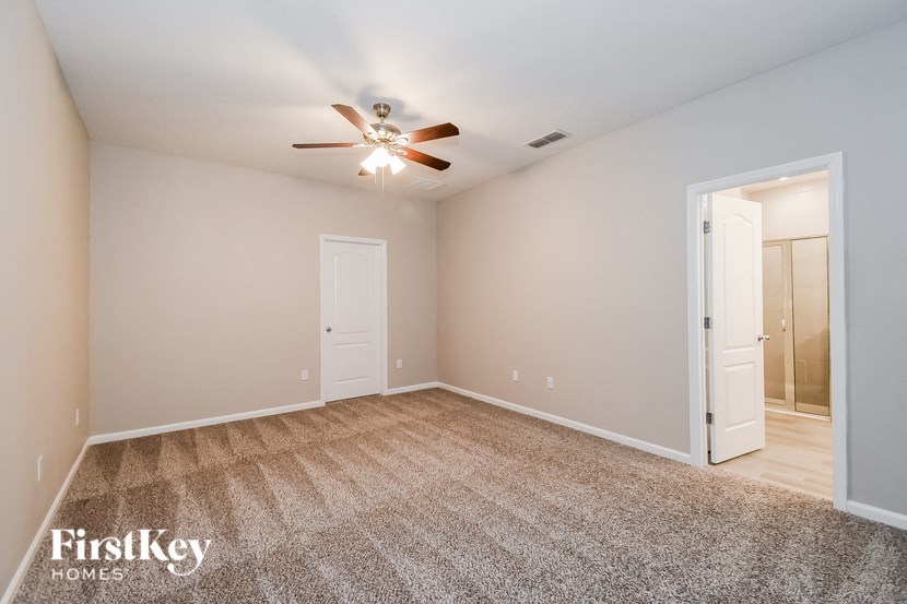 A spacious room with a carpeted floor and a ceiling fan.