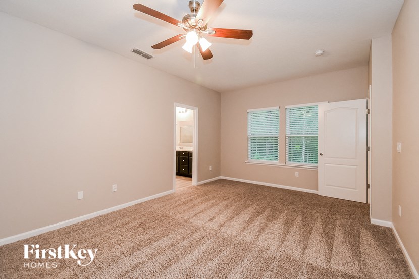 A room with a carpet floor and a ceiling fan.