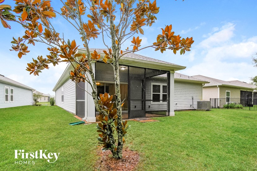 A tree with orange leaves stands in front of a house.