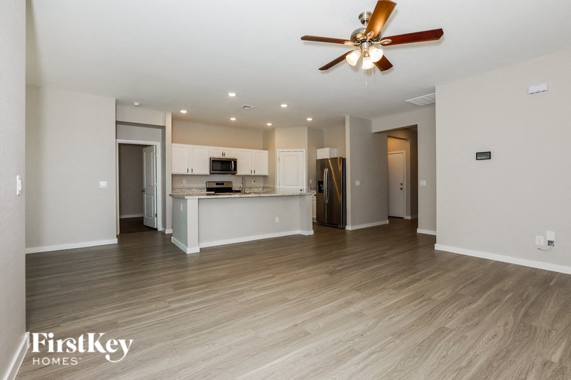 an empty living room and kitchen with a ceiling fan