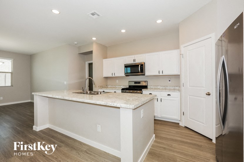 a kitchen with white cabinets and a marble counter top