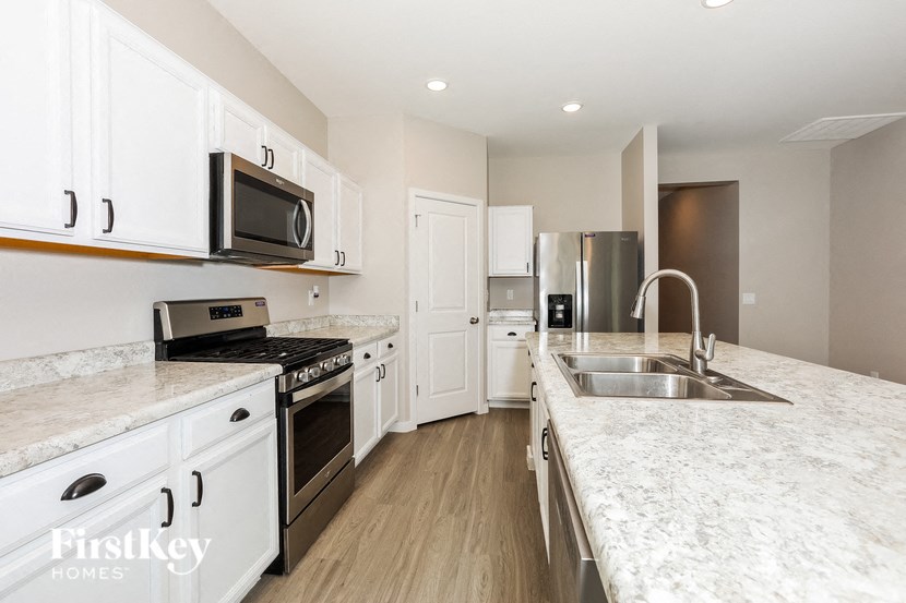 a kitchen with marble counter tops and white cabinets and stainless steel appliances