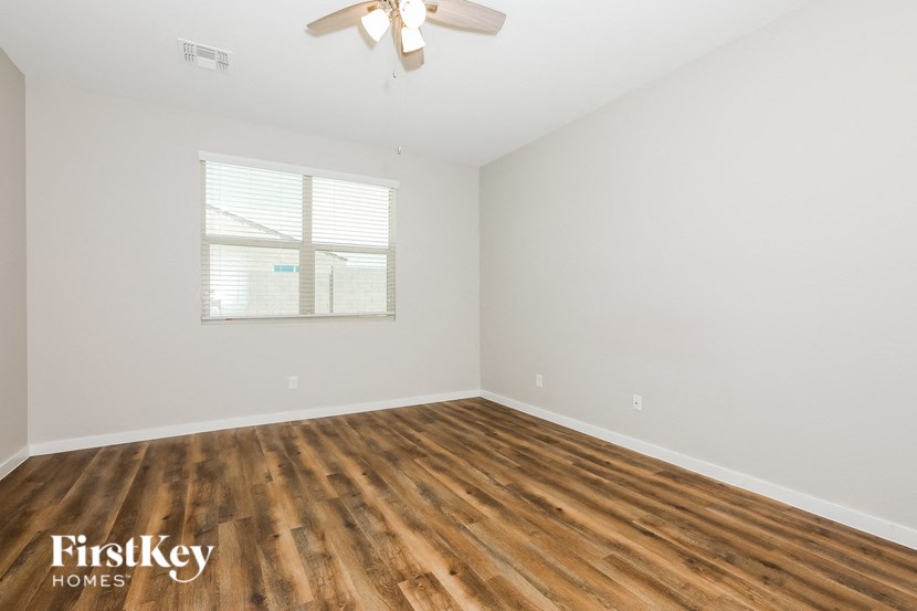 a bedroom with white walls and wood flooring and a window