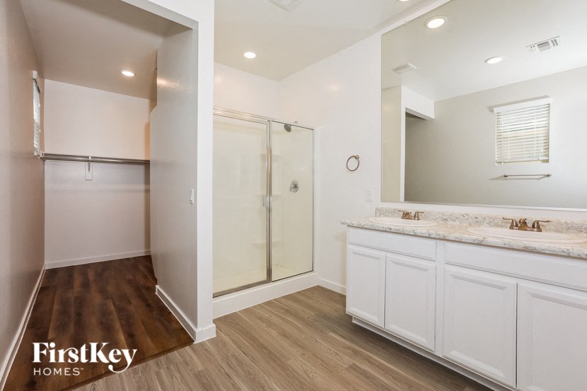 a bathroom with white cabinets and a shower and a sink