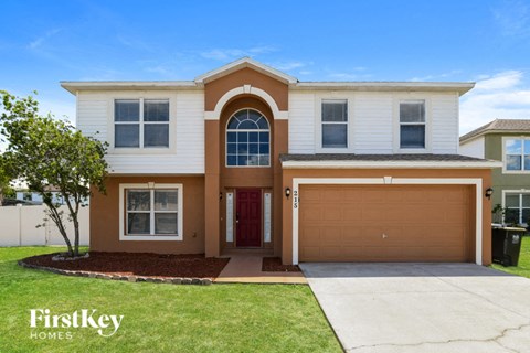 A two-story house with a red door and a brown garage door.