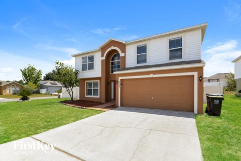 A two-story house with a brown garage door is for sale.