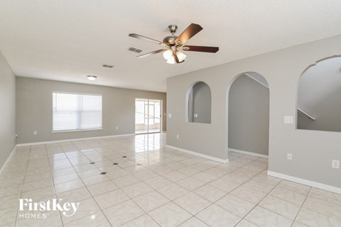 A spacious room with a ceiling fan and arched windows.