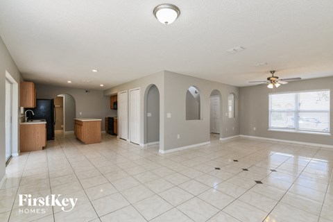 A spacious empty room with a ceiling fan and a large window.