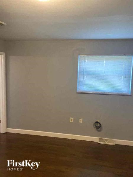 an empty room with a window and a hard wood floor
