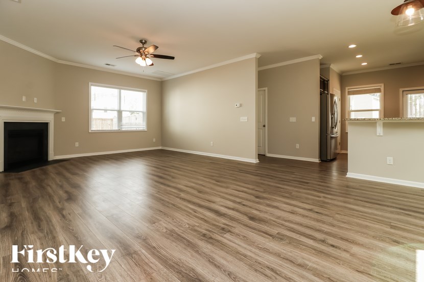 A spacious room with wooden flooring and a ceiling fan.