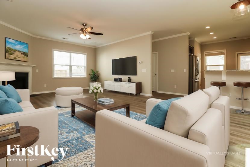A living room with a white sofa, a coffee table, and a flat screen TV.