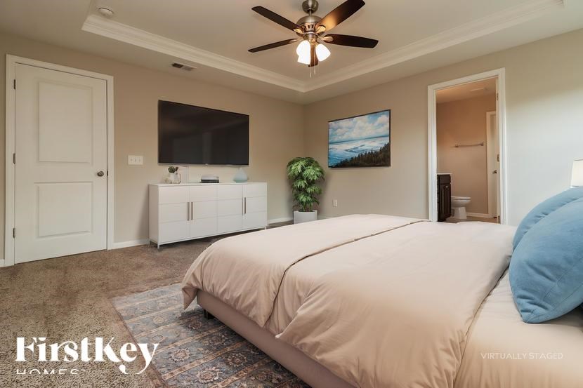 A bedroom with a bed, a ceiling fan, and a television.