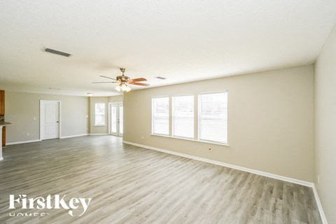 A spacious room with wooden flooring and a ceiling fan.