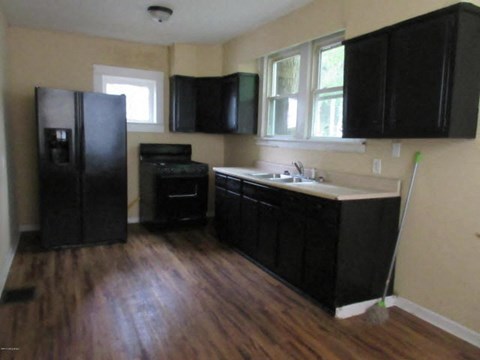 A kitchen with black cabinets and a black fridge.