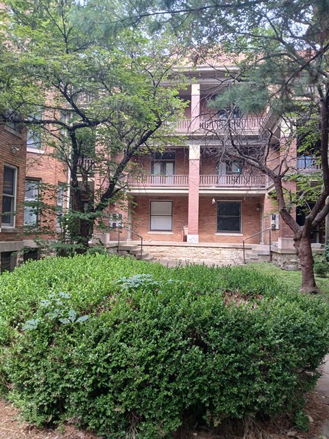a brick building with trees and bushes in front of it