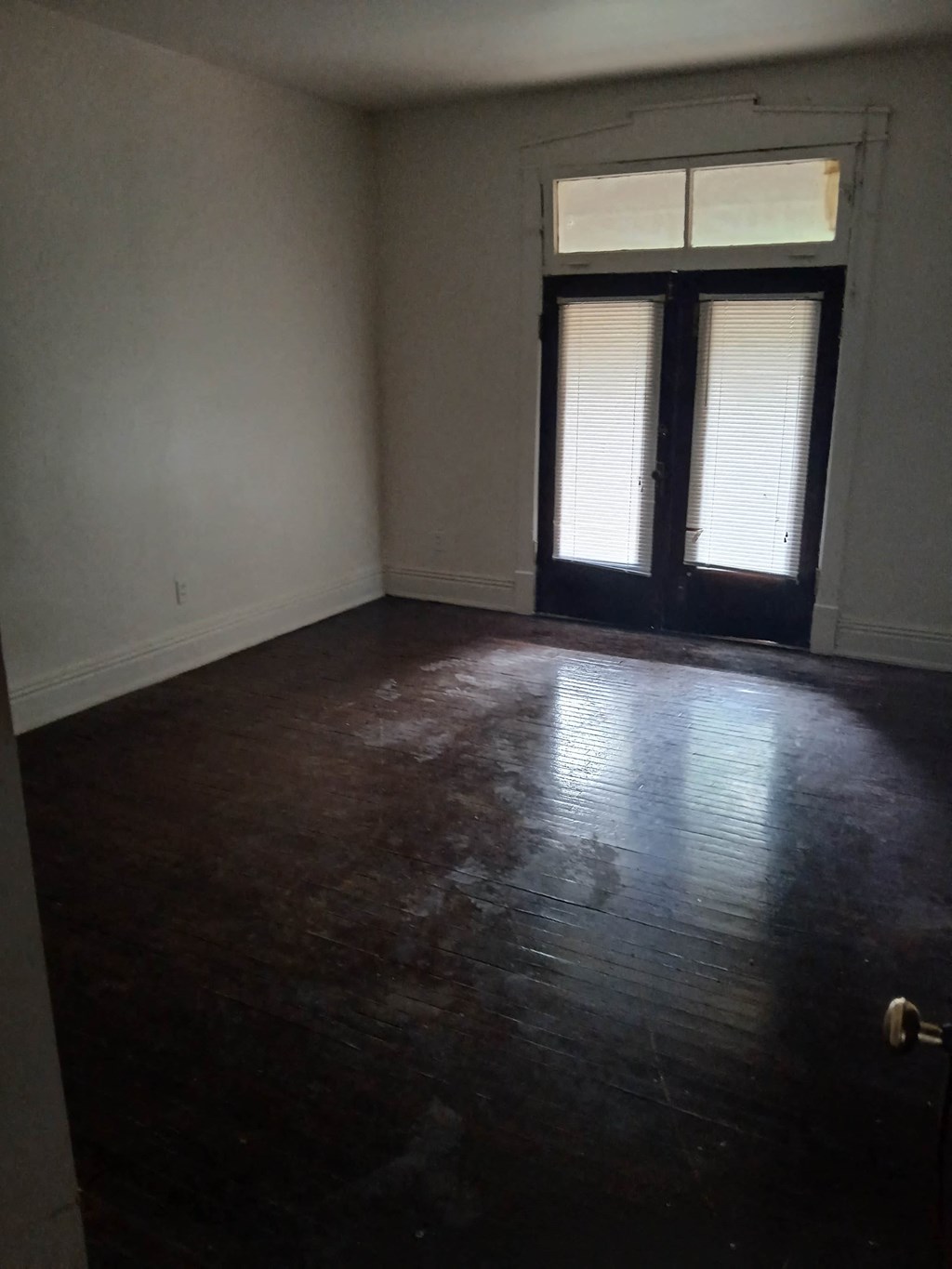 an empty living room with a wooden floor and a door