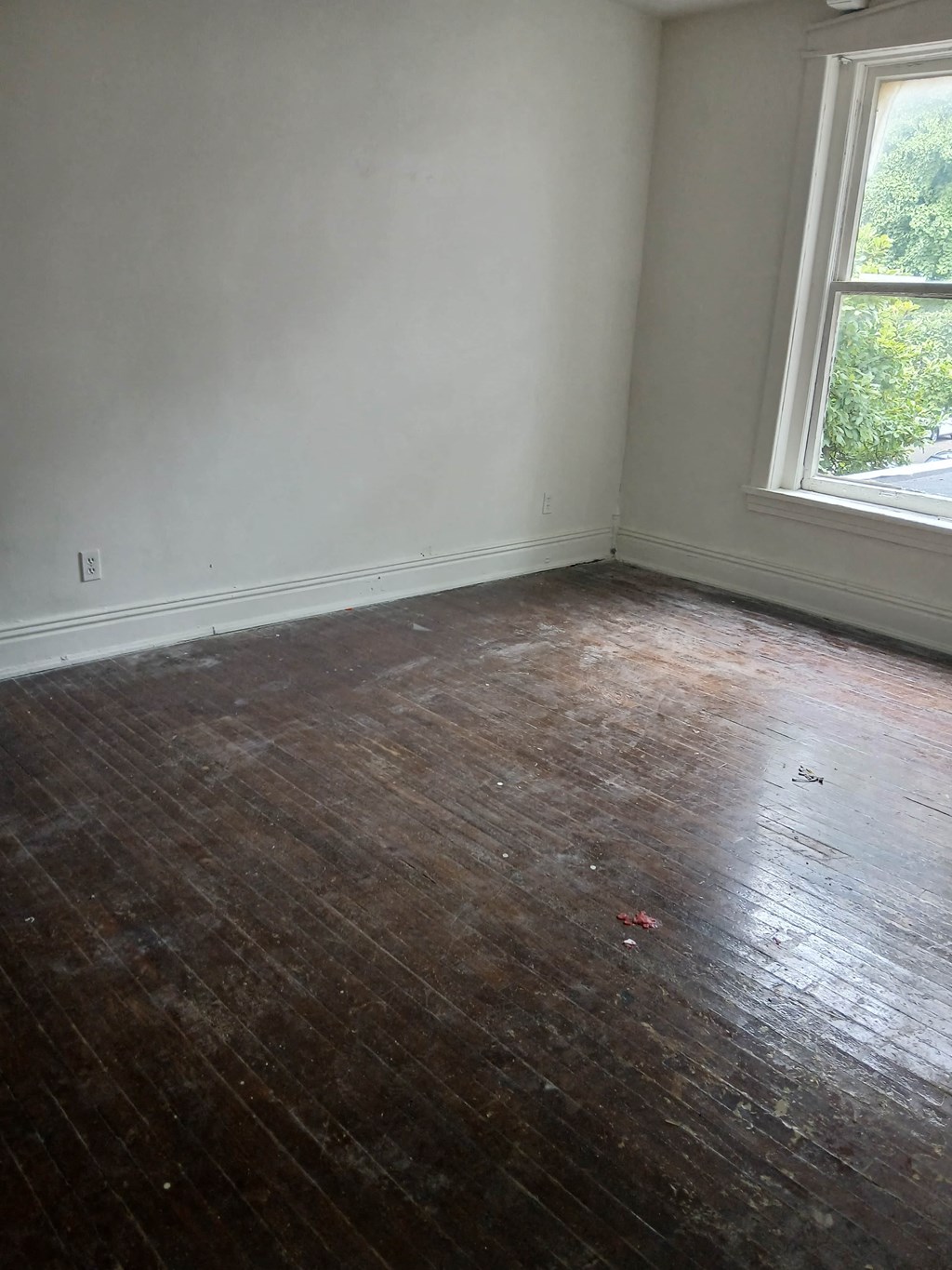 an empty room with a wooden floor and a window