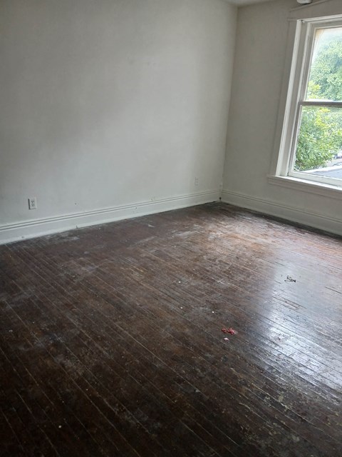 an empty room with a wooden floor and a window