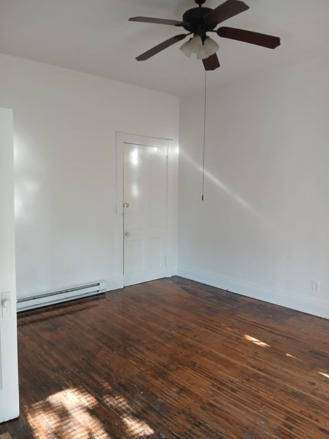 an empty room with a ceiling fan and wood floors