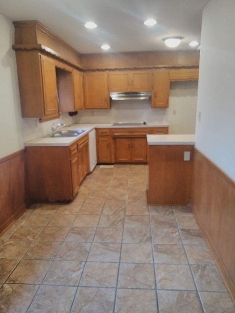 an empty kitchen with wooden cabinets and tiled floors