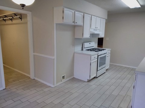 A white kitchen with a stove top oven and white cabinets.