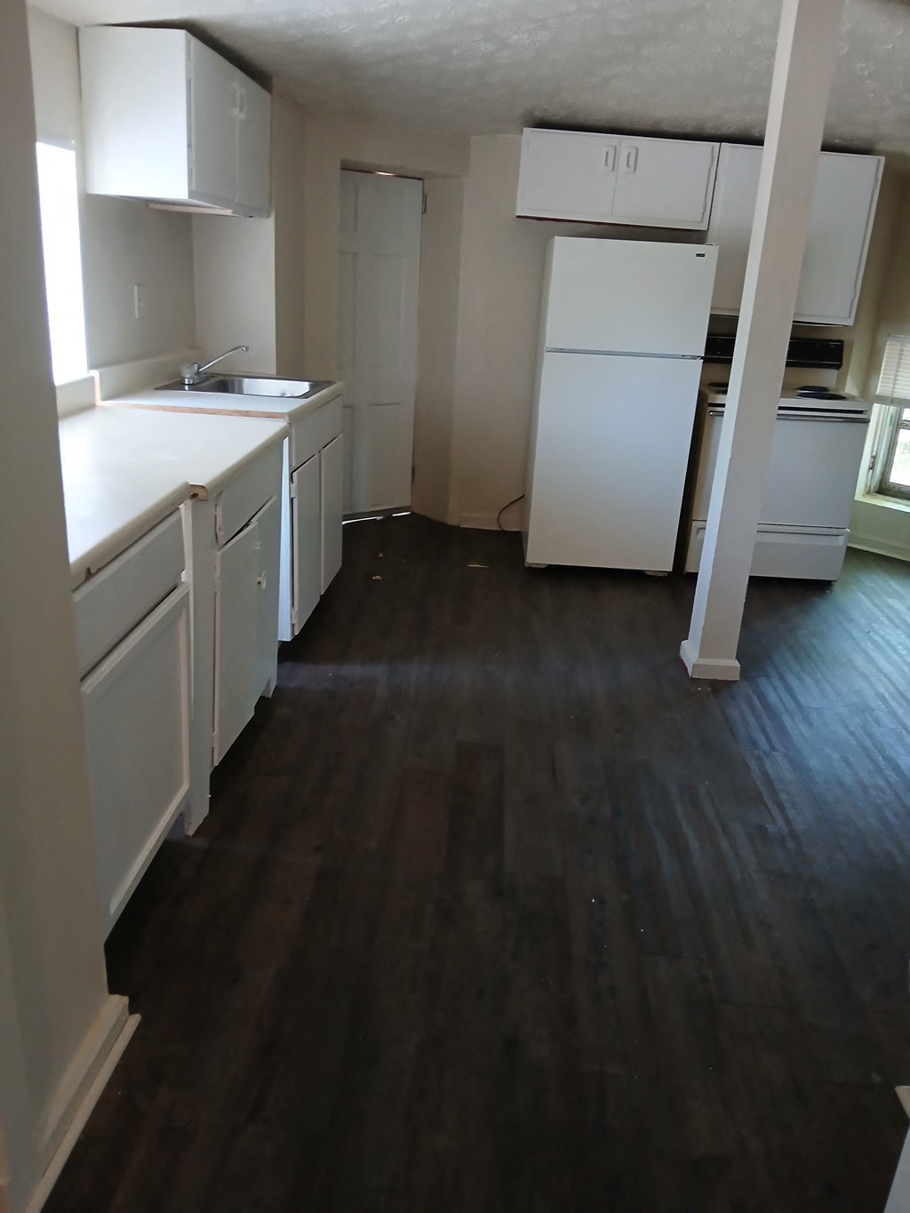 an empty kitchen with wooden floors and white cabinets