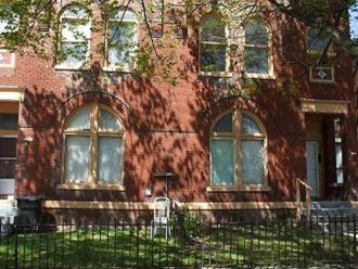 a red brick building with windows and a fence