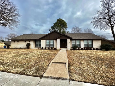front view of a white brick house with a lawn and a sidewalk