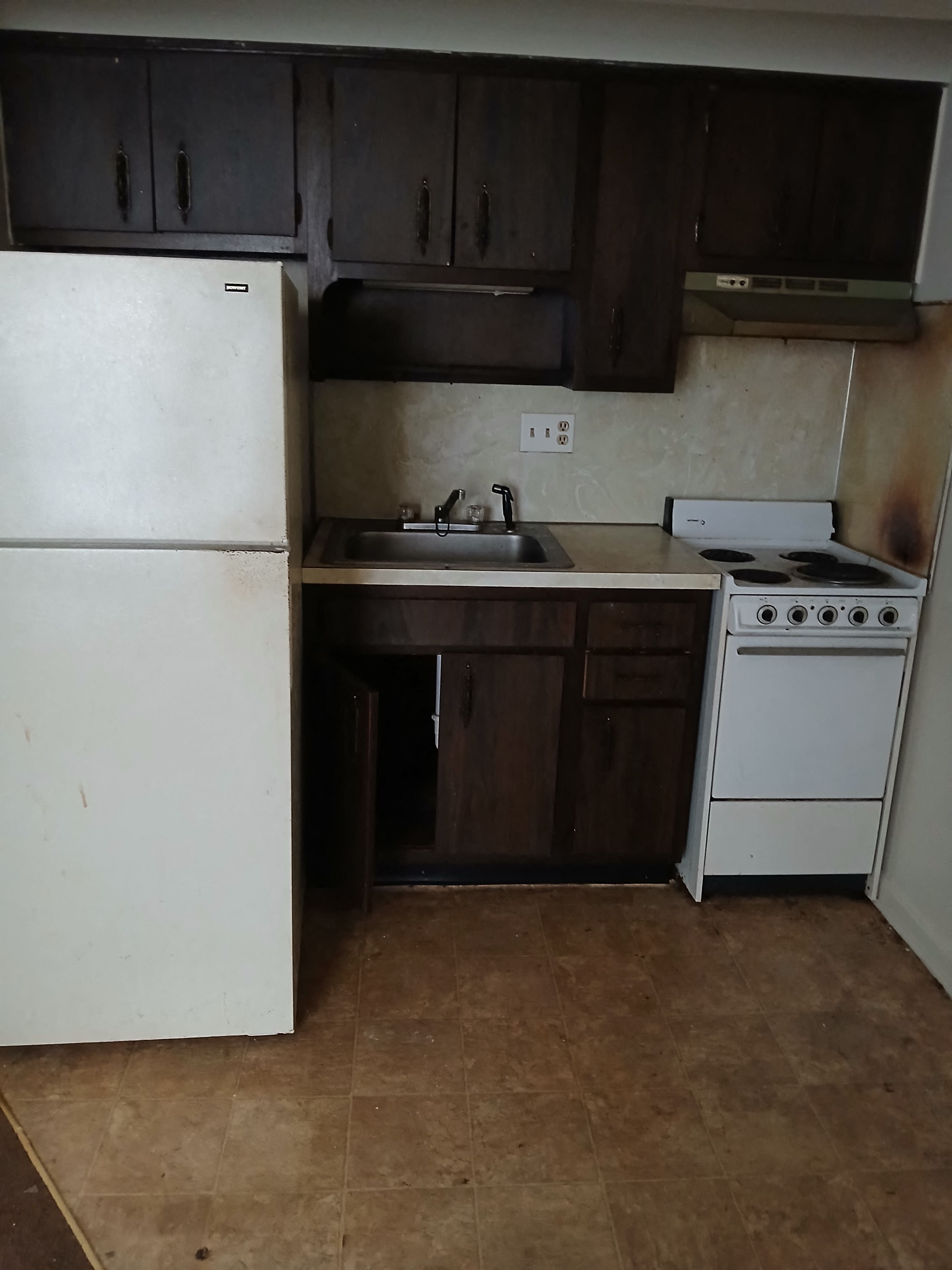 an empty kitchen with a stove refrigerator and sink