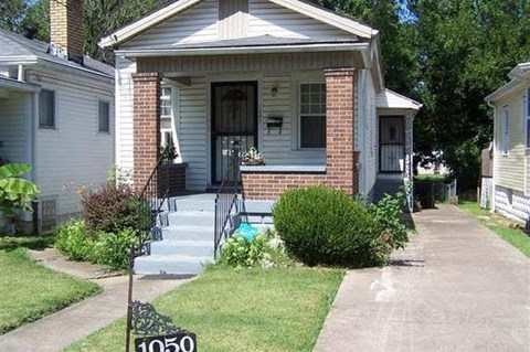 A house with a front porch and a mailbox on the lawn.