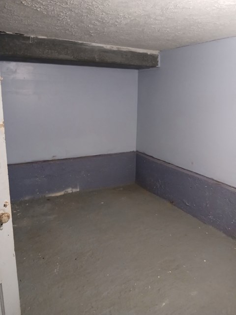 A room with a white door and a concrete floor.