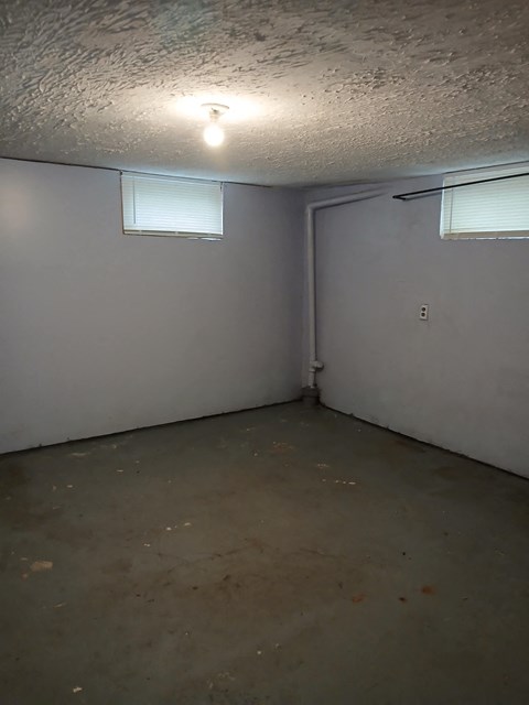 A room with a light on the ceiling and a window with blinds.