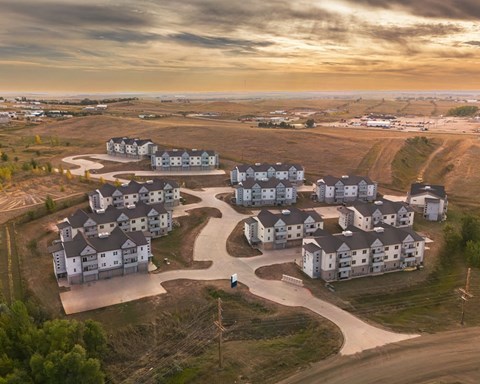 an aerial view of a group of houses on a dirt road near a field