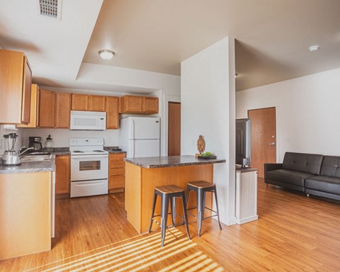a living room with a kitchen and a bar with two stools