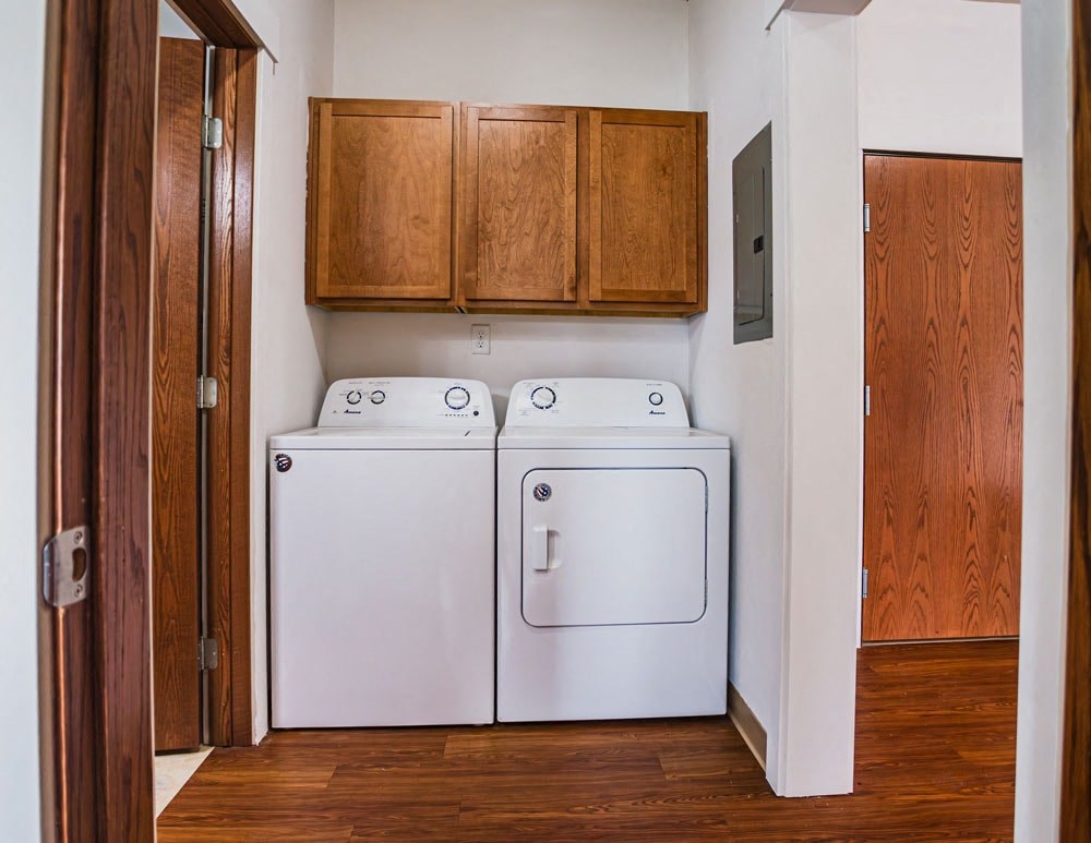 a washer and dryer in a laundry room with wooden cabinets