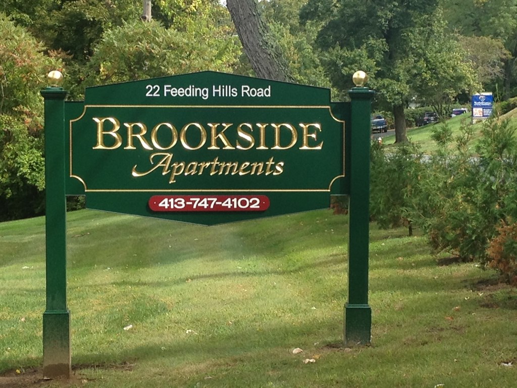 a green sign that reads   in a park