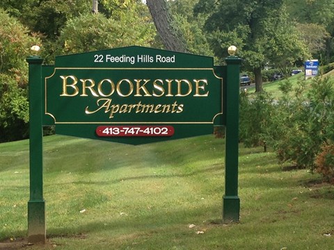 a green sign that reads   in a park