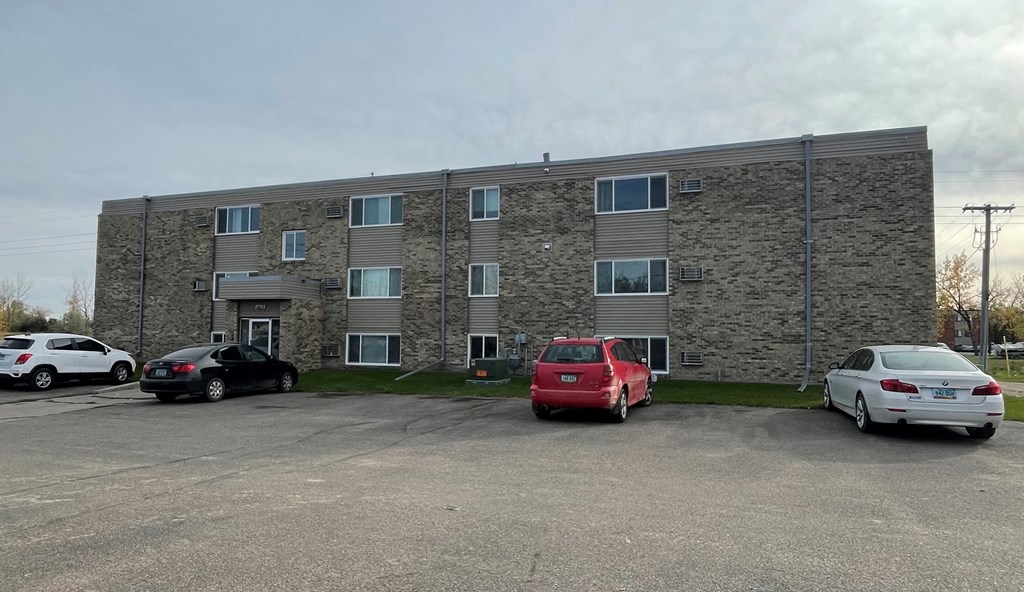 an apartment building with cars parked in front of it