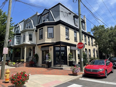 A red car is parked at a stop sign on a street.