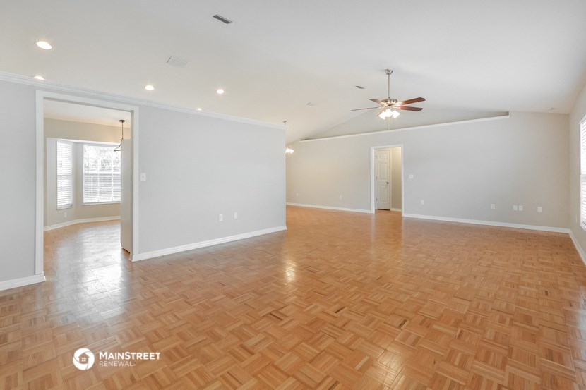 the spacious living room with wood flooring and a ceiling fan