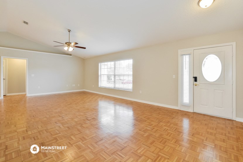an empty living room with wood flooring and a white door