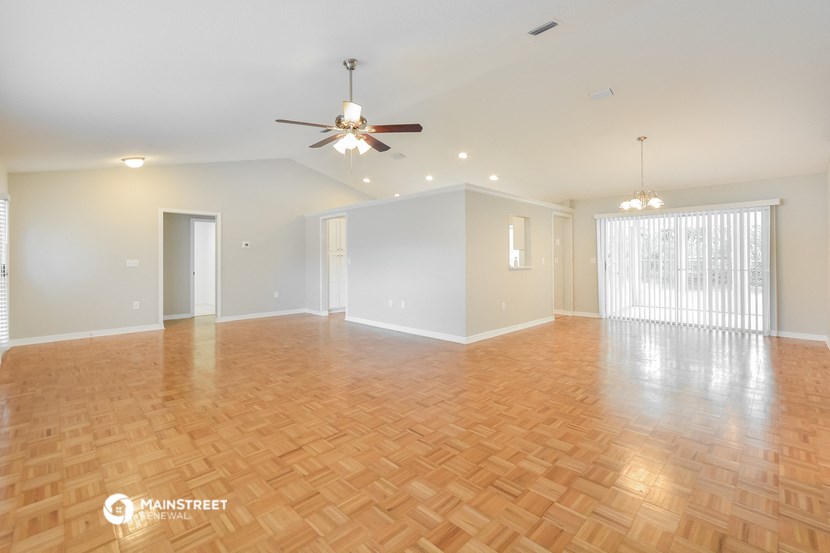 an empty living room with wood flooring and a ceiling fan