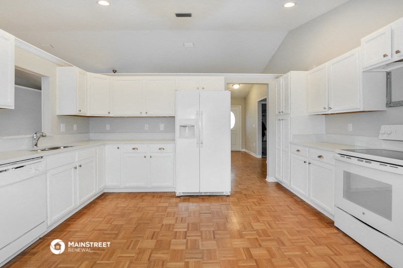 a large white kitchen with white cabinets and a wooden floor