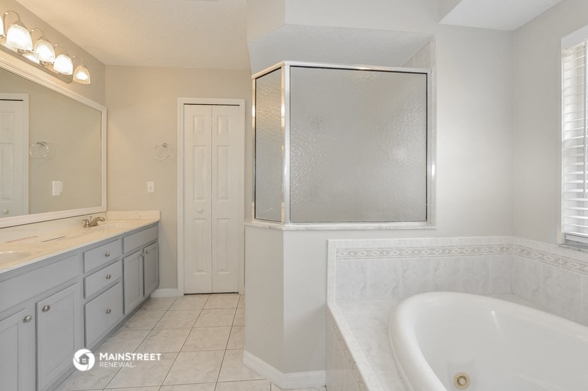 a white bathroom with a tub and a sink and a mirror